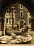 Student sitting in an arched walkway of the Hall of Graduate Studies.
