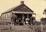 African Americans on porch of cabin.