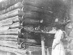 Woman standing outside a cabin, reaching for an African-American child in window.