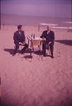 William C. Bullitt sitting at a table on the beach.