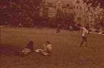 Students playing football and a couple lounging in a residential college courtyard.